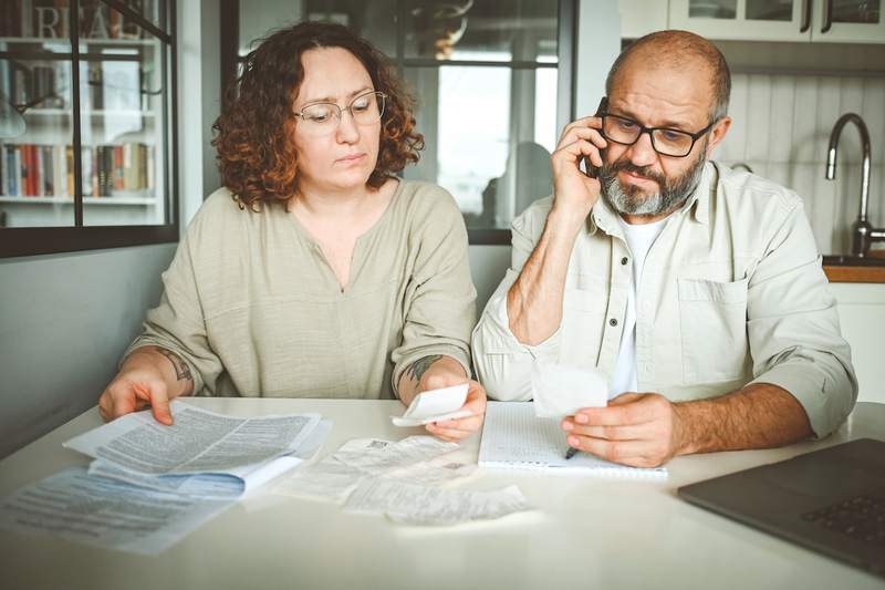 A woman and a man review their finances at the kitchen table.