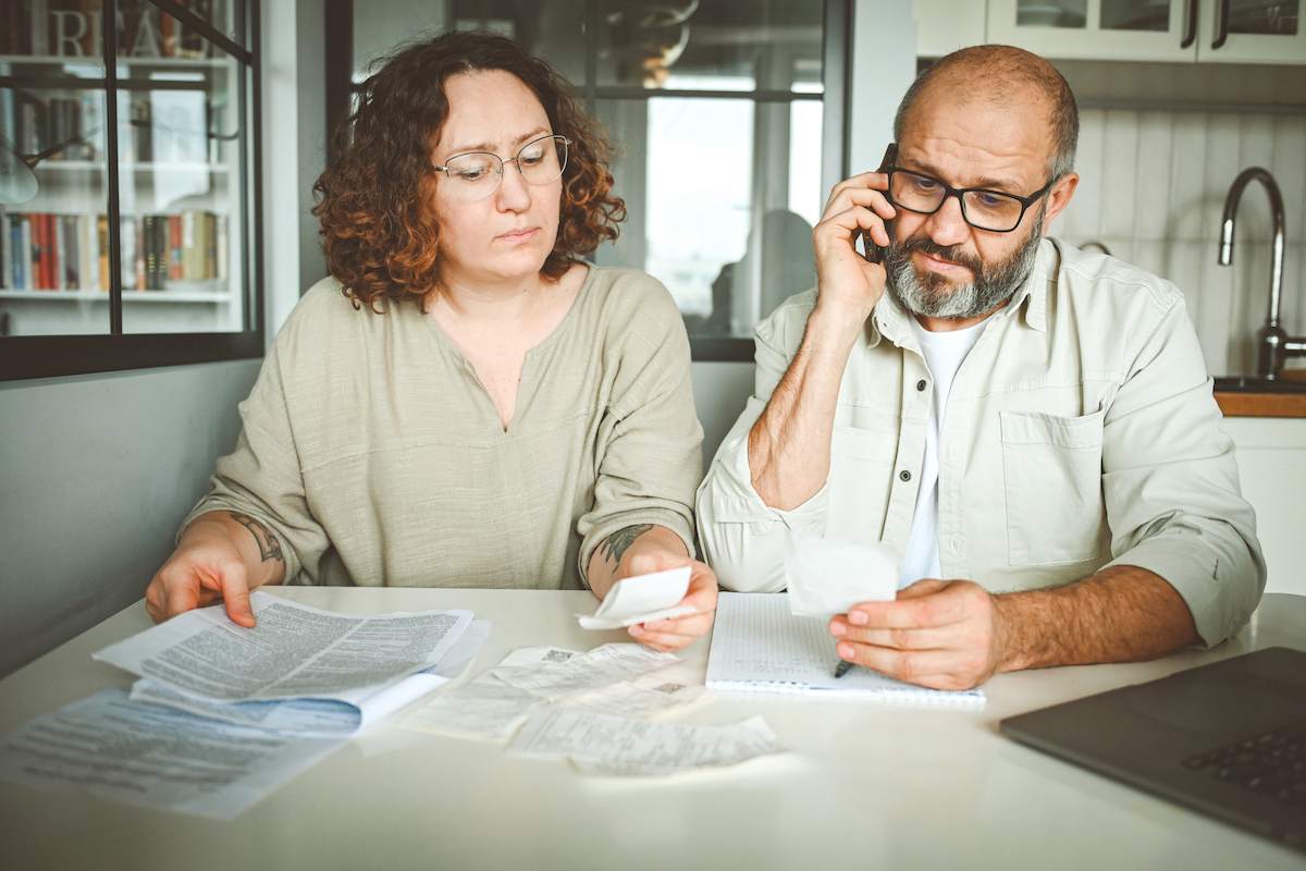 A woman and a man review their finances at the kitchen table.